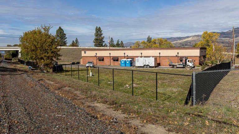 Workers (at left) install new security and privacy fencing at the Ashland emergency homeless shelter, 2200 Ashland St. in 2023. Construction to bring the emergency shelter up to fire code is nearly complete. Ashland.news photo by Bob Palermini