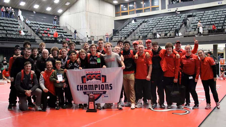 Southern Oregon wrestlers and coaches pose with the Cascade Conference championship banner and trophy earned Saturday in Redding, California. Courtney Blumer photo