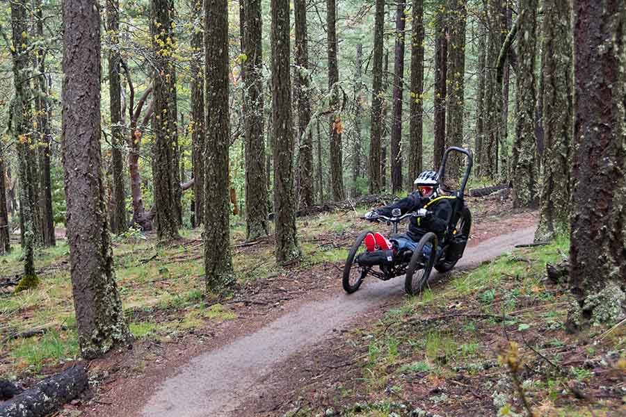 Tammie Thompson rides a trail on her custom mountain bike, which is actually a three-wheeler. Members of the Rogue Valley Mountain Bike Association widened a part of Ashland's trail network to handle her bike. Thompson, who lost the use of her legs in an accident, loves what mountain biking does for her body and spirit. Ryan Hawk photo