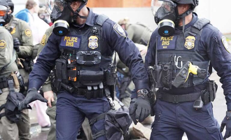 Department of Homeland Security police, along with other federal police, push and tackle protesters at the Immigration and Customs Enforcement facility south of downtown Portland on Sunday, Oct. 12, 2025. Oregon Capital Chronicle photo by Alex Baumhardt